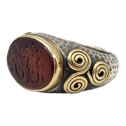 65 - A PERSIAN BIMETAL AND GARNET INTAGLIO GENTS SIGNET RING
Oval stone with Islamic inscription and scro... 