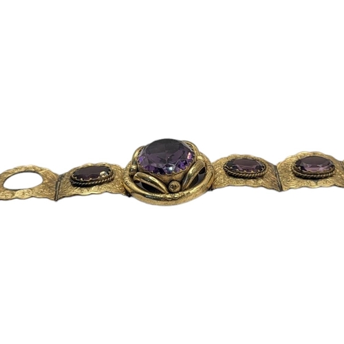 93 - A VICTORIAN GILT METAL AND AMETHYST GLASS BRACELET
Set with oval faceted stones in engraved decorati... 