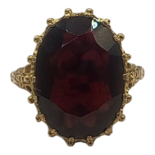 76A - A VINTAGE 9CT GOLD AND GARNET RING
Having an oval faceted cut stone in a pierced and scrolled mount.... 