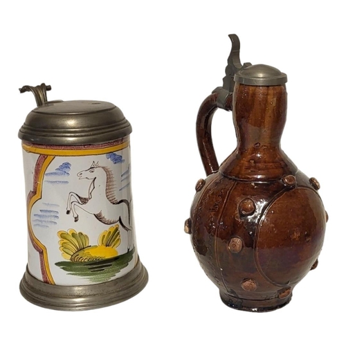 215 - A 19TH CENTURY GERMAN POTTERY AND PEWTER FLAGON
Having a single handle and incised and applied decor... 