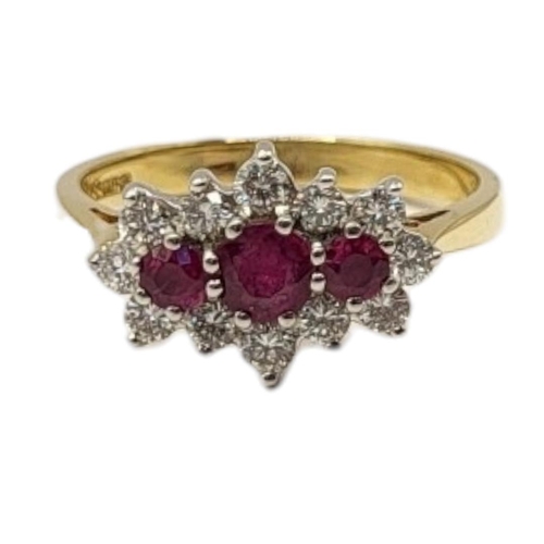 23 - AN 19CT GOLD, RUBY AND DIAMOND CLUSTER RING
The row of three graduated round cut rubies edged with r... 