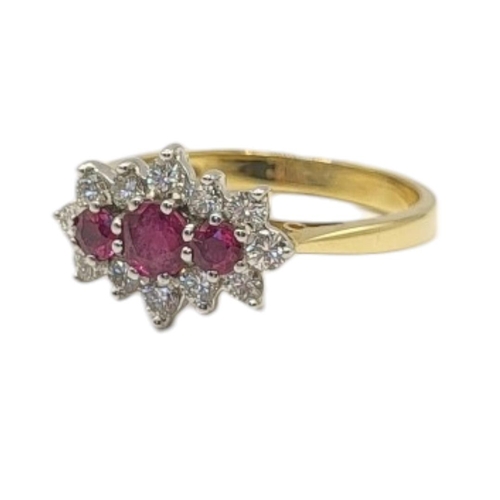 23 - AN 19CT GOLD, RUBY AND DIAMOND CLUSTER RING
The row of three graduated round cut rubies edged with r... 