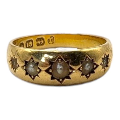 26 - AN EARLY 20TH CENTURY 18CT GOLD AND SEED PEARL RING 
Having a row of graduated pearls in a rubover s... 