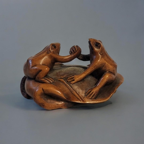 276 - A 20TH CENTURY JAPANESE CARVED WOODEN NETSUKE
Two frogs shaking hands on a lily pad, signed to base.... 