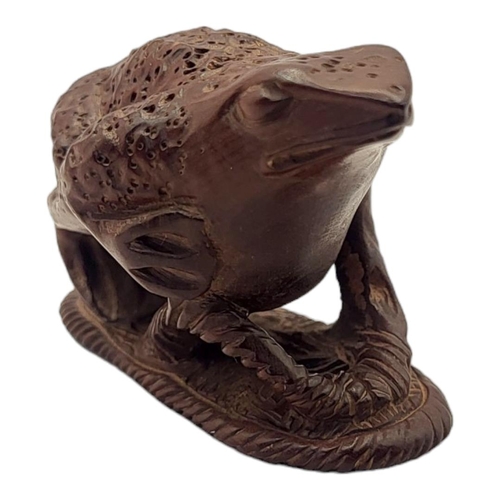 294 - A JAPANESE WOODEN TOAD NETSUKE
Sat on a sandal with maker’s mark to base. 
(5.5cm x 3cm x 4cm)

Cond... 