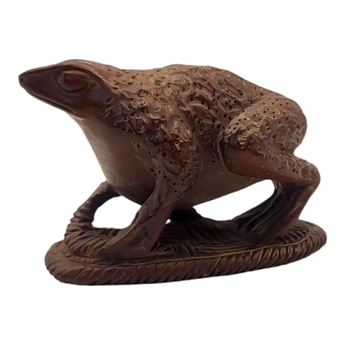 294 - A JAPANESE WOODEN TOAD NETSUKE
Sat on a sandal with maker’s mark to base. 
(5.5cm x 3cm x 4cm)

Cond... 