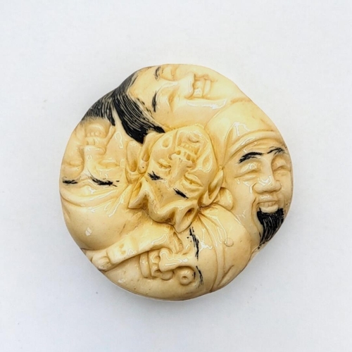 308 - A JAPANESE BONE NETSUKE
Circular form, with carved stylised faces to body. 
(4cm x 1.5cm)

Condition... 