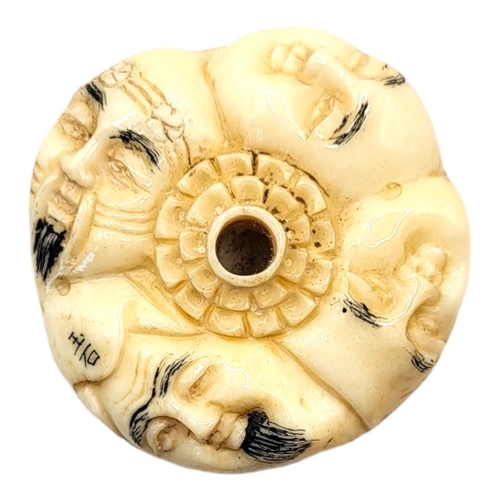 308 - A JAPANESE BONE NETSUKE
Circular form, with carved stylised faces to body. 
(4cm x 1.5cm)

Condition... 