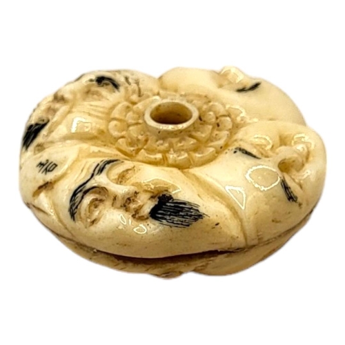 308 - A JAPANESE BONE NETSUKE
Circular form, with carved stylised faces to body. 
(4cm x 1.5cm)

Condition... 