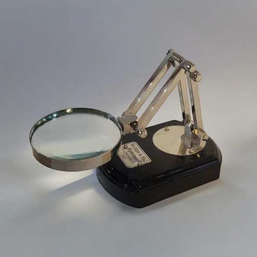 313 - AN EARLY 19TH CENTURY STYLE CHROME ANGLEPOISE MAGNIFYING GLASS
On an ebonised wooden plinth. 
(9cm x... 