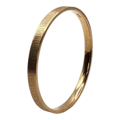 34 - A VINTAGE 9CT GOLD BANGLE
Having fine engraved  Greek key decoration, inscribed date to interior 192... 