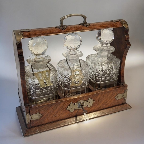 363 - AN EARLY 20TH CENTURY OAK AND CUT GLASS TANTALUS
Having silver plated corners, Bramah lock and three... 