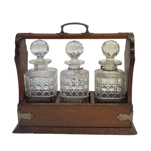 363 - AN EARLY 20TH CENTURY OAK AND CUT GLASS TANTALUS
Having silver plated corners, Bramah lock and three... 