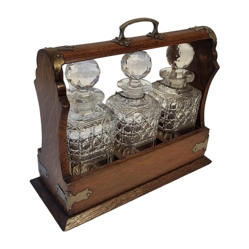 363 - AN EARLY 20TH CENTURY OAK AND CUT GLASS TANTALUS
Having silver plated corners, Bramah lock and three... 