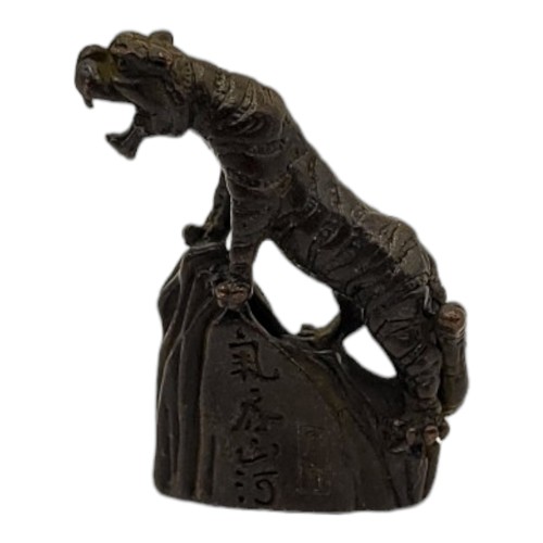 239A - A BRONZE MEIJI STYLE TIGER
Standing on rock impressed with Japanese characters. 
(5cm x 5cm)

Condit... 