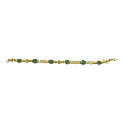 122 - A VINTAGE CHINESE YELLOW METAL AND JADE BRACELET
Cabochon cut stones in a pierced design.
(approx 17... 