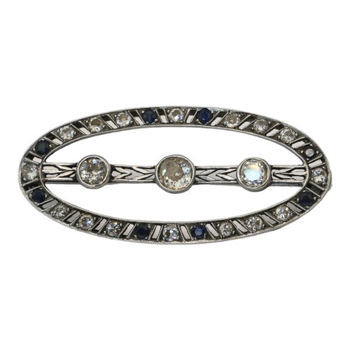 54 - AN ART DECO WHITE METAL, DIAMOND AND SAPPHIRE OVAL BROOCH
Edged with sapphire and diamonds with thre... 