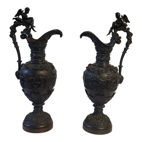 242 - A PAIR OF CONTINENTAL BRONZE FIGURAL EWERS
Classical form, with winged cherub finial,vine leaves and... 