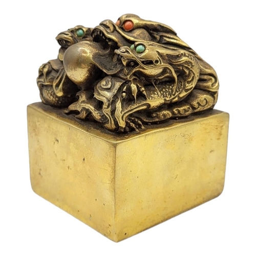 337 - A CHINESE BRONZE DRAGON SEAL
The eyes inset with coloured stones on a patinated body, with inscribed... 