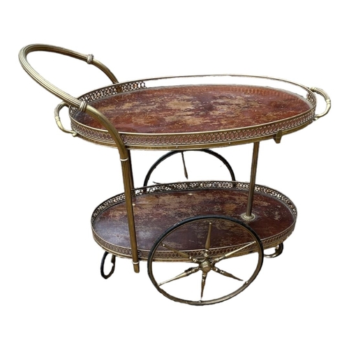 542 - A VINTAGE BRASS AND MAHOGANY TWO TIER TRAY TOP DRINKS TROLLEY
With pierced galleries, spindled wheel... 