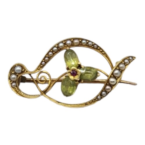 142 - AN EDWARDIAN 15CT GOLD PERIDOT, RUBY AND SEED PEARL BROOCH
The central ruby edged with three oval cu... 