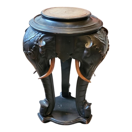 592 - A LATE VICTORIAN EBONISED MAHOGANY PLANT STAND
The circular top on three carved elephant legs standi... 