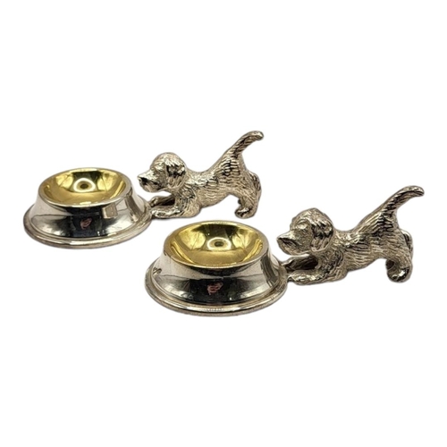 56 - A PAIR OF SILVER PLATED DOG SALTS
The bodies hovering over a polished basin. 
(5.5cm x 10cm x 4cm)

... 