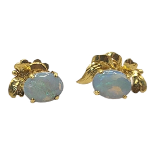 65 - A VINTAGE PAIR OF 18CT GOLD AND OPAL EARRINGS 
The single cabochon cut stone on a floral mount.
(opa... 