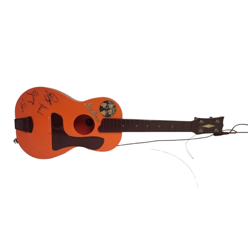 328A - THE BEATLES, A MID CENTURY PLASTIC TOY GUITAR
Orange plastic with facsimile signatures and sticker a... 