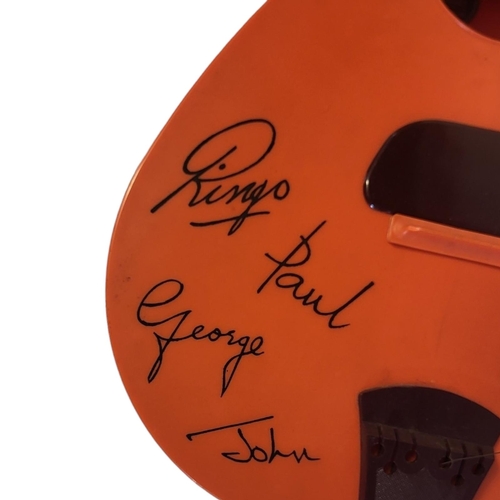 328A - THE BEATLES, A MID CENTURY PLASTIC TOY GUITAR
Orange plastic with facsimile signatures and sticker a... 