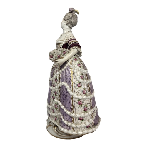 718 - A 19TH CENTURY CONTINENTAL PORCELAIN FIGURE OF LADY WITH FAN
Wearing an elaborate ballroom gown of 1... 