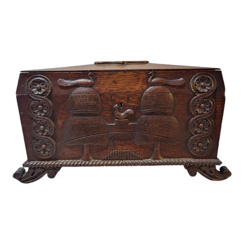 104 - AN EARLY 19TH CENTURY CARVED OAK TEA CADDY
Sarcophagus form with foliate shield to lid, twin handles... 