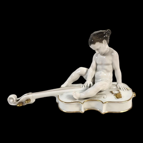 222 - FERDINAND LIBERMANN, 1883 - 1941, FOR ROSENTHAL, A PORCELAIN MODEL OF A CHERUB BOY SEATED ON A CELLO... 