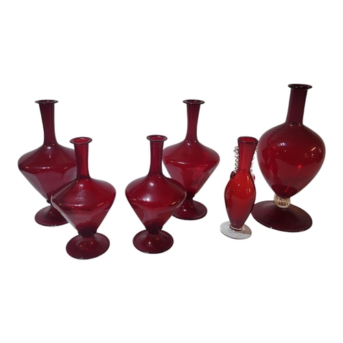 125 - A SET OF TWELVE MURANO EARLY 20TH CENTURY IRON RED GLAZED WINE CARAFES 
One with ribbed spiralling g... 