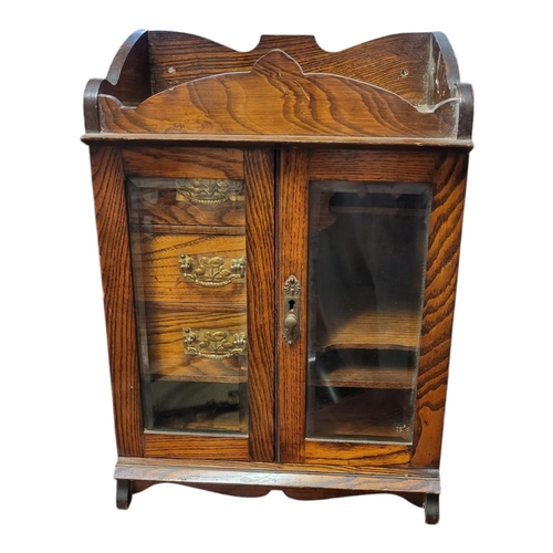 144 - A LATE VICTORIAN SOLID OAK SMOKER’S CABINET 
With galleried top above two bevelled glazed doors encl... 