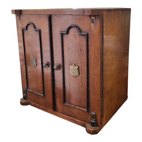 145 - A LATE VICTORIAN SOLID OAK SMOKER’S CABINET 
The two doors enclosing two short and one long drawer, ... 