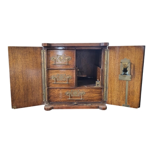 145 - A LATE VICTORIAN SOLID OAK SMOKER’S CABINET 
The two doors enclosing two short and one long drawer, ... 