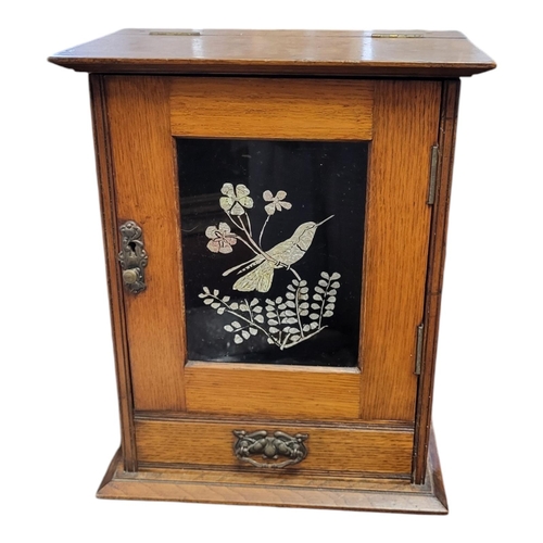 146 - A LATE VICTORIAN OAK SMOKER’S CABINET
With rise and fall top, single door inset with foil bird panel... 