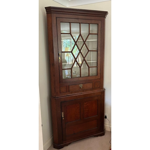 486 - A GEORGIAN OAK FLOOR STANDING CORNER CABINET
With single glazed door above a single drawer and cupbo... 