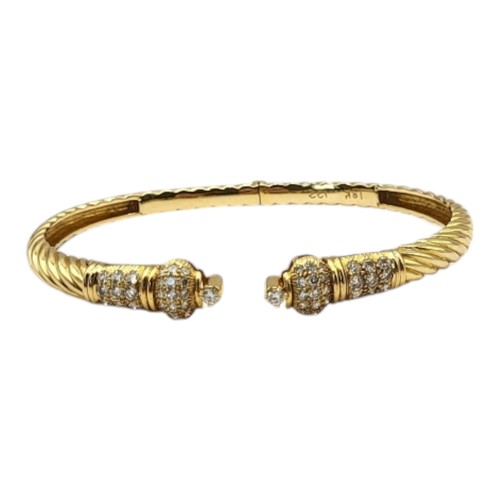 49A - AN 18CT GOLD AND DIAMOND BANGLE
Having an arrangement of round cut diamonds in a wreathed design wit... 