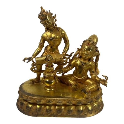 214 - A TIBETAN BUDDHIST GILT BRONZE STATUE OF ACHALA & TARA
The decorative bodies and urn inset with red ... 