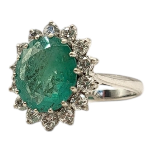 19 - AN 18CT GOLD, EMERALD AND DIAMOND CLUSTER RING
The central oval faceted cut emerald edged with round... 