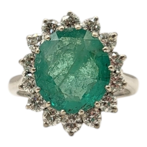 19 - AN 18CT GOLD, EMERALD AND DIAMOND CLUSTER RING
The central oval faceted cut emerald edged with round... 