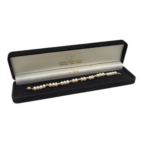 98 - A VINTAGE 18CT GOLD AND PEARL BRACELET
The single strand of button form freshwater pearls interspers... 