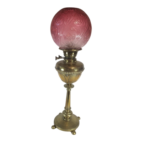 131 - AN ART NOUVEAU CRANBERRY GLASS AND BRASS OIL LAMP
Globular form shade, with embossed floral design o... 