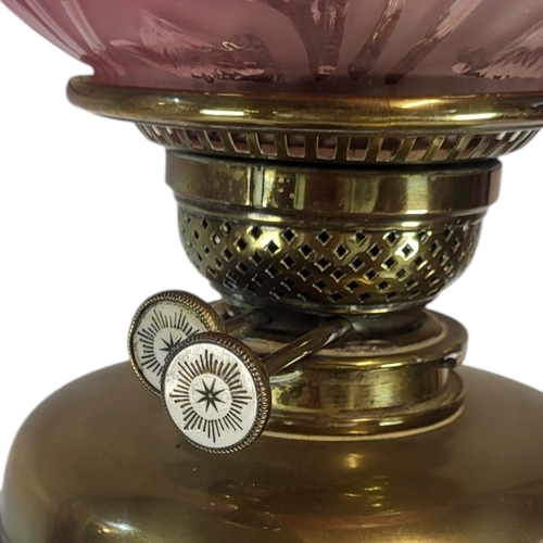 131 - AN ART NOUVEAU CRANBERRY GLASS AND BRASS OIL LAMP
Globular form shade, with embossed floral design o... 