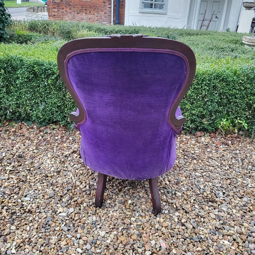 324 - A VICTORIAN MAHOGANY FRAMED SPOON BACK ARMCHAIR
In deep purple button back upholstery, scroll arm, o... 