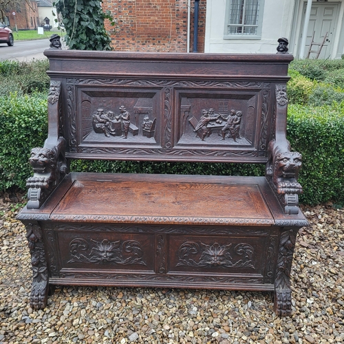 329 - A VICTORIAN OAK TWO SEAT SETTLE
With facial mask finials above panels carved with tavern scenes, arm... 