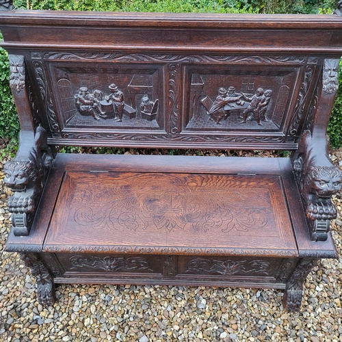 329 - A VICTORIAN OAK TWO SEAT SETTLE
With facial mask finials above panels carved with tavern scenes, arm... 