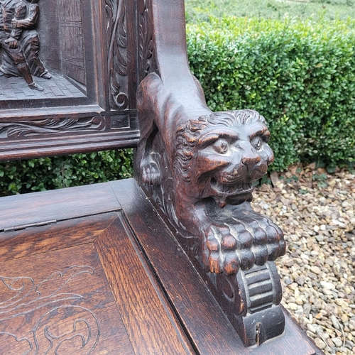 329 - A VICTORIAN OAK TWO SEAT SETTLE
With facial mask finials above panels carved with tavern scenes, arm... 